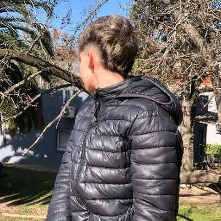 MaurooAkd de espaldas con campera negra, mirando a un costado en un parque